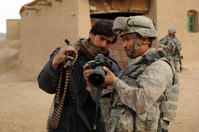 A combat photographer preparing to capture a gruesome scene.